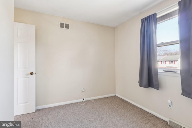 carpeted spare room featuring visible vents and baseboards