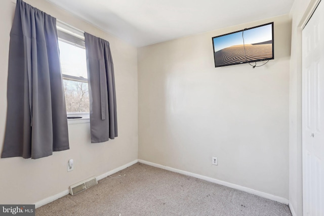 spare room featuring carpet, visible vents, and baseboards