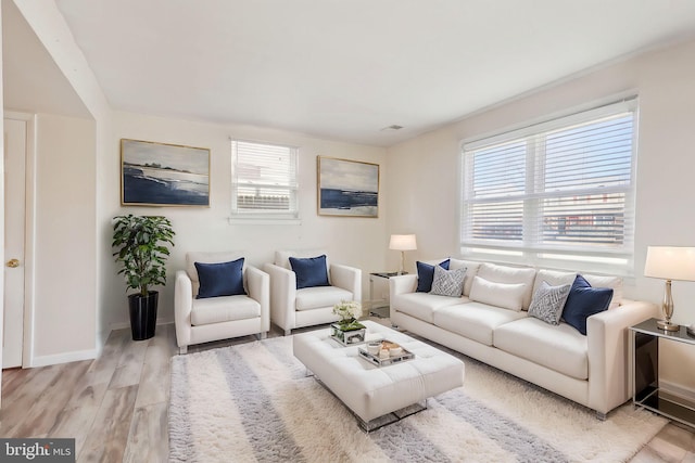 living area featuring visible vents, light wood finished floors, a wealth of natural light, and baseboards