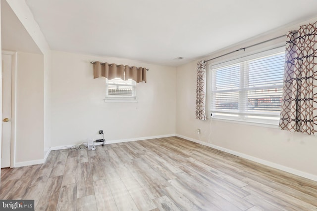 spare room with visible vents, baseboards, and wood finished floors