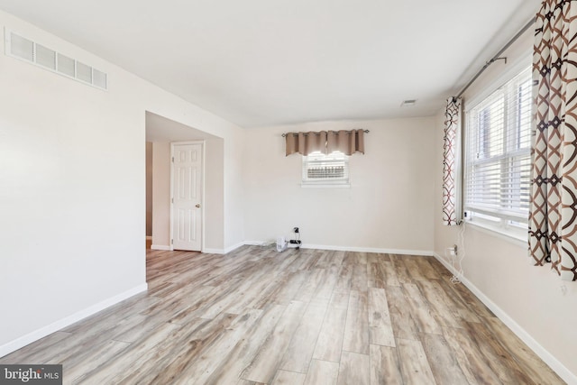 empty room featuring visible vents, plenty of natural light, and wood finished floors