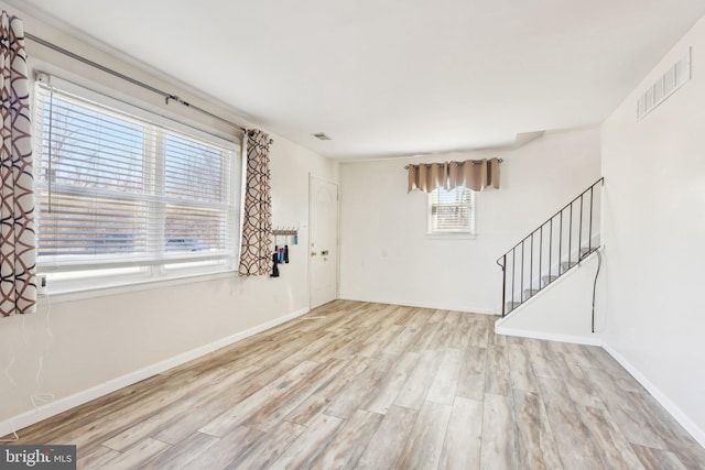 unfurnished living room featuring stairway, baseboards, visible vents, and wood finished floors