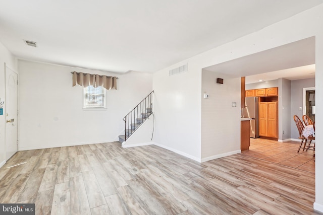 interior space with light wood-style floors, visible vents, and stairs