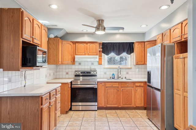 kitchen featuring light countertops, appliances with stainless steel finishes, a ceiling fan, a sink, and under cabinet range hood