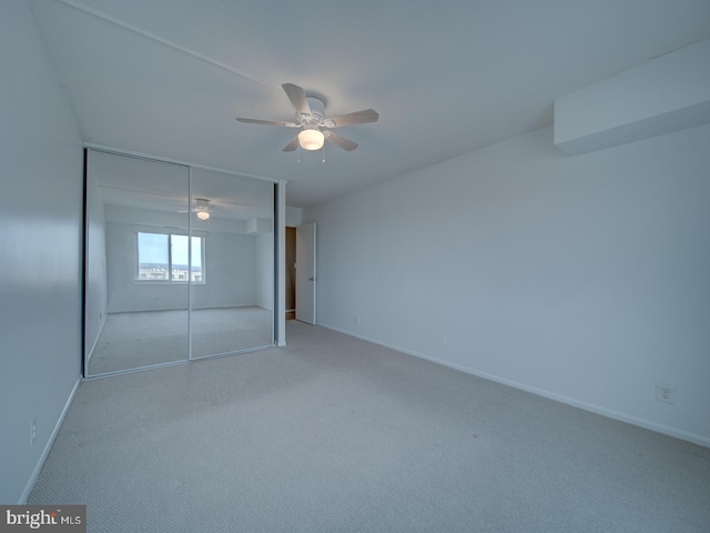 unfurnished bedroom with ceiling fan, a closet, baseboards, and carpet flooring