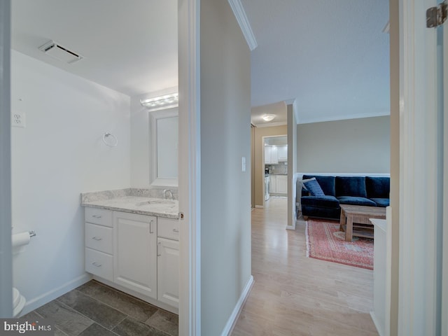 bathroom with crown molding, visible vents, vanity, wood finished floors, and baseboards