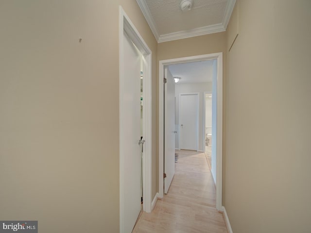 hallway featuring ornamental molding, light wood-style floors, and a textured ceiling