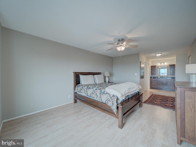 bedroom featuring light wood-style floors, a ceiling fan, baseboards, and connected bathroom