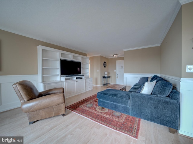 living room with a wainscoted wall, crown molding, and light wood-style flooring