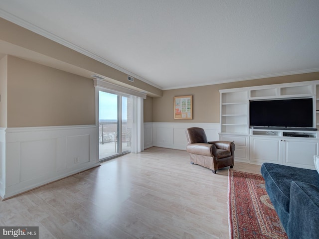 sitting room featuring visible vents, crown molding, and light wood finished floors