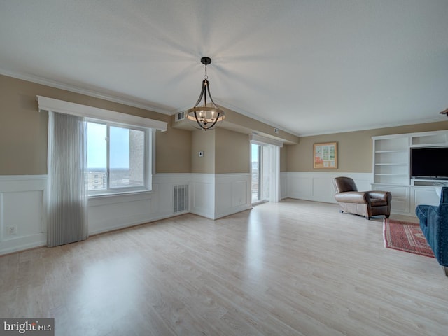 unfurnished room featuring an inviting chandelier, visible vents, wood finished floors, and a wainscoted wall