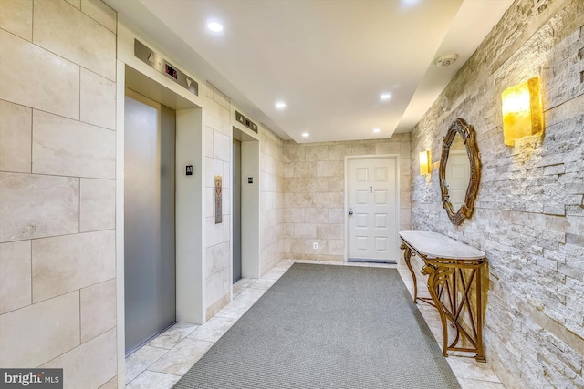 hallway featuring recessed lighting, elevator, tile walls, and light tile patterned floors