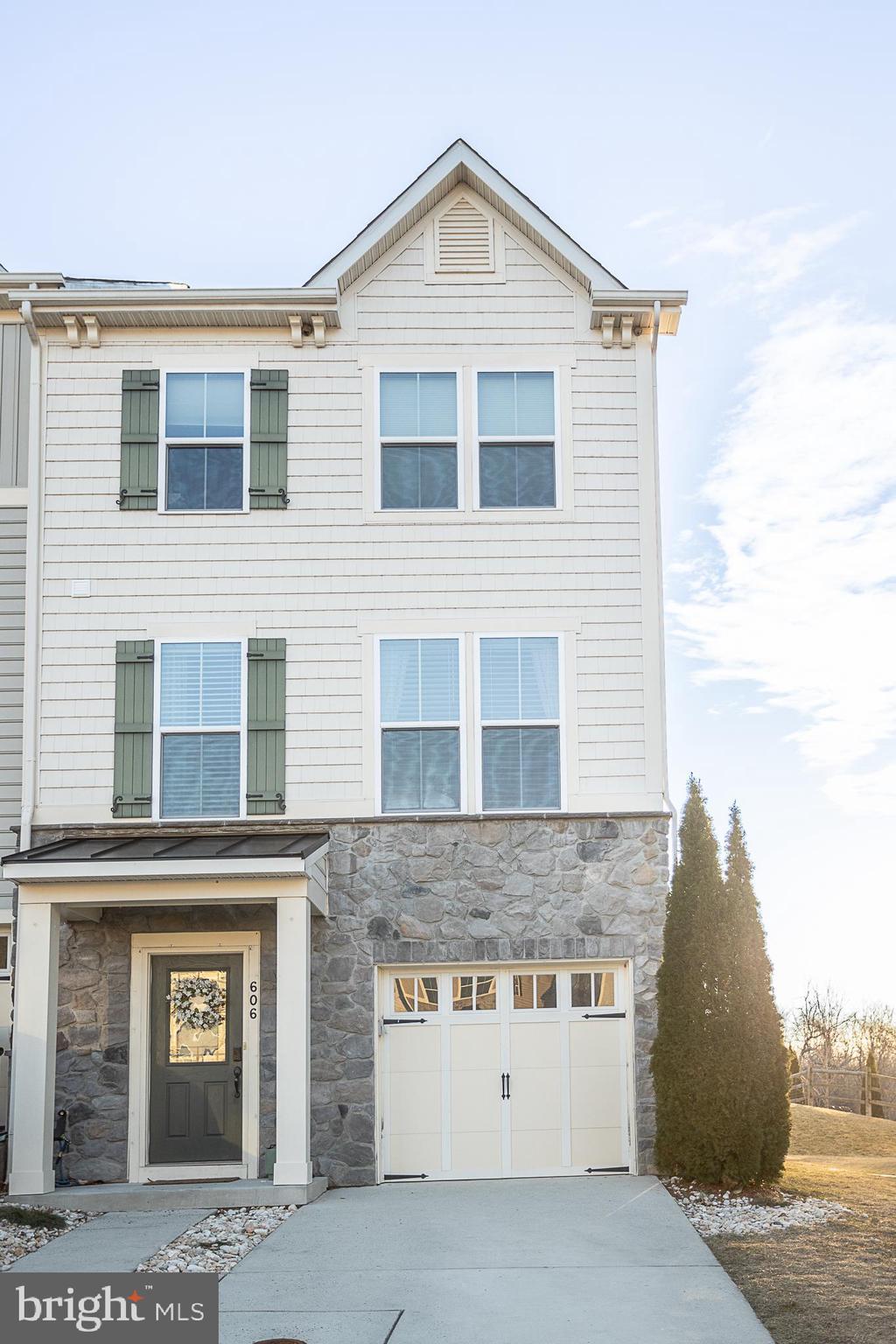 view of front of home featuring a garage, stone siding, and concrete driveway