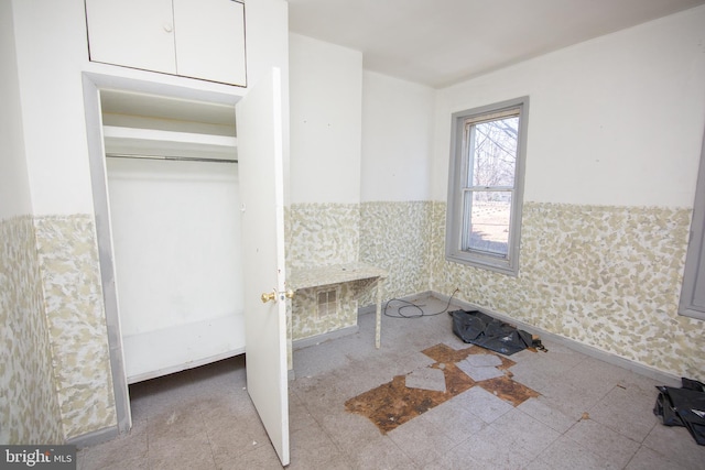 interior space featuring wallpapered walls, tile patterned floors, and wainscoting