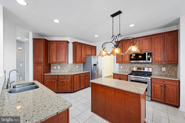 kitchen with appliances with stainless steel finishes, a sink, light stone counters, and a kitchen island