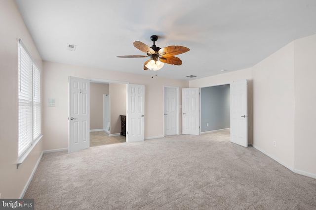 unfurnished bedroom featuring baseboards, visible vents, a ceiling fan, and light colored carpet