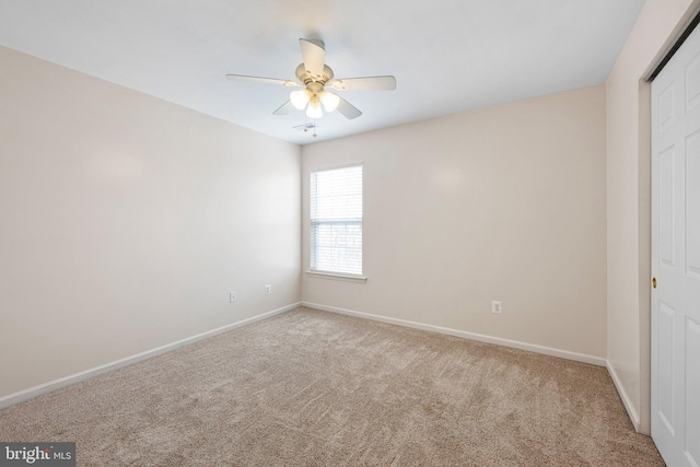 carpeted empty room featuring ceiling fan and baseboards