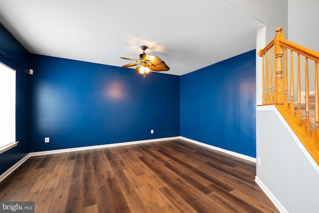 spare room featuring ceiling fan, stairs, baseboards, and wood finished floors