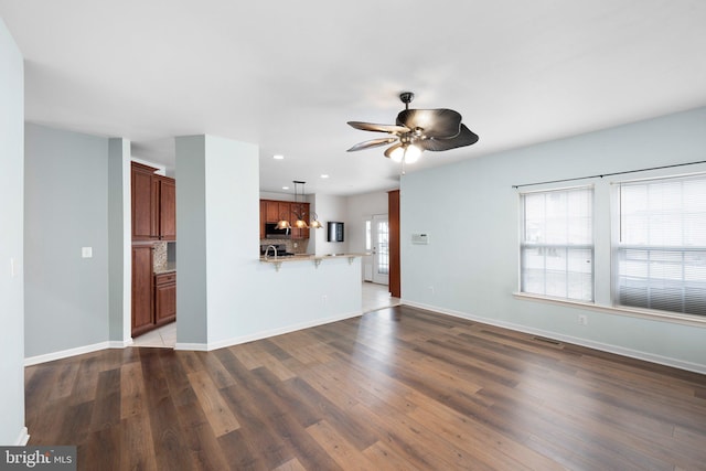 unfurnished living room with baseboards, visible vents, ceiling fan, wood finished floors, and recessed lighting