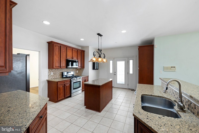 kitchen featuring a notable chandelier, stainless steel appliances, a sink, decorative backsplash, and pendant lighting