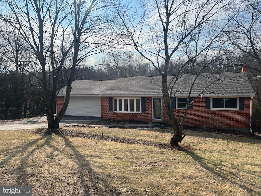 ranch-style house featuring brick siding, a shingled roof, a front yard, driveway, and an attached garage