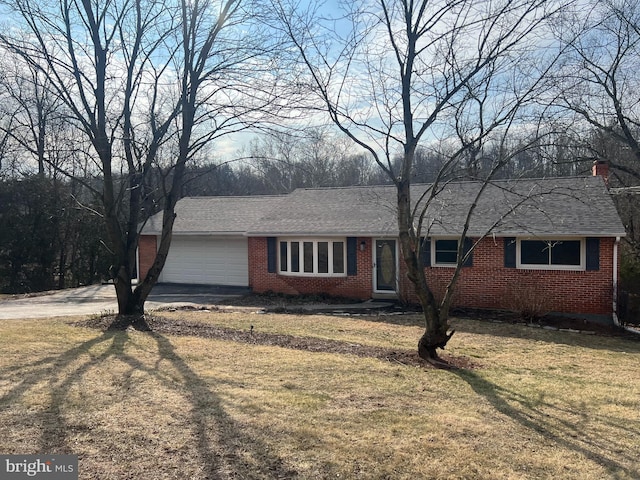 ranch-style house featuring brick siding, a shingled roof, a front yard, driveway, and an attached garage