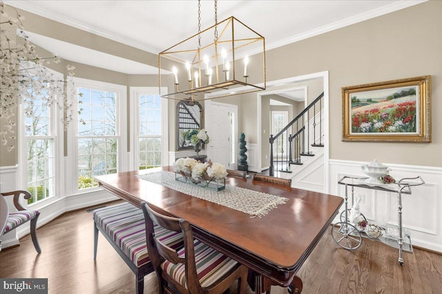 dining area with stairs, wainscoting, wood finished floors, and crown molding