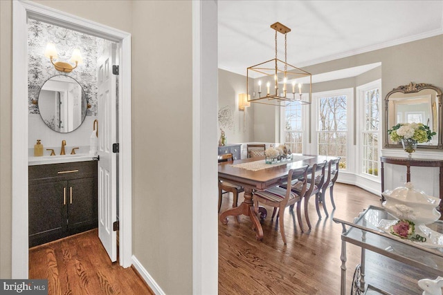 dining space with ornamental molding, a chandelier, baseboards, and wood finished floors