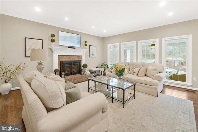 living room with a wealth of natural light, a fireplace, visible vents, and wood finished floors