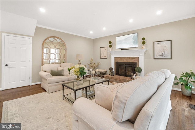 living room featuring baseboards, a fireplace, wood finished floors, and crown molding