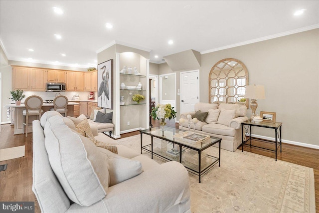 living room featuring ornamental molding, recessed lighting, baseboards, and light wood finished floors