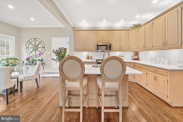 kitchen featuring stainless steel microwave, light countertops, decorative backsplash, and light brown cabinetry