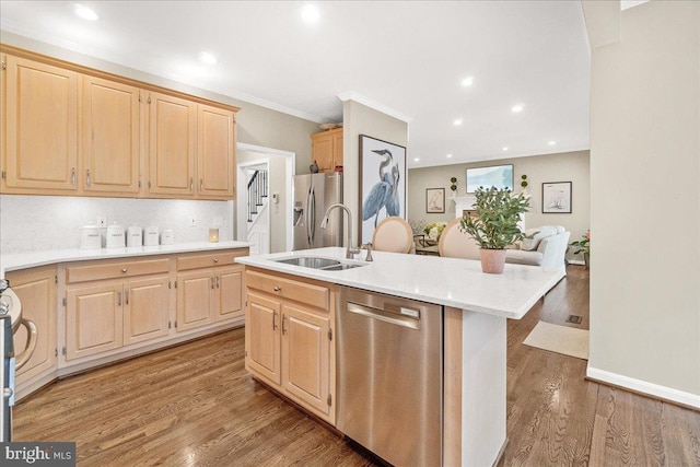 kitchen with appliances with stainless steel finishes, wood finished floors, light countertops, light brown cabinetry, and a sink