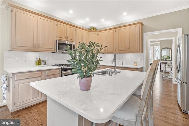 kitchen featuring tasteful backsplash, light wood-style flooring, appliances with stainless steel finishes, ornamental molding, and a sink