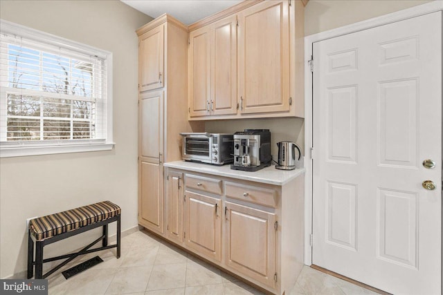 interior space featuring a toaster, visible vents, baseboards, and light tile patterned floors