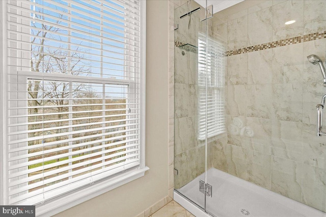 bathroom with a shower stall, a wealth of natural light, and baseboards