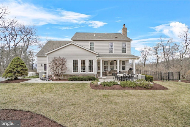 rear view of property featuring a shingled roof, a lawn, a patio, a chimney, and fence