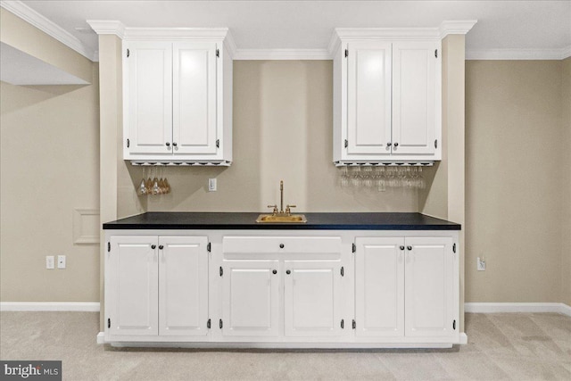 kitchen with light carpet, ornamental molding, dark countertops, and white cabinets