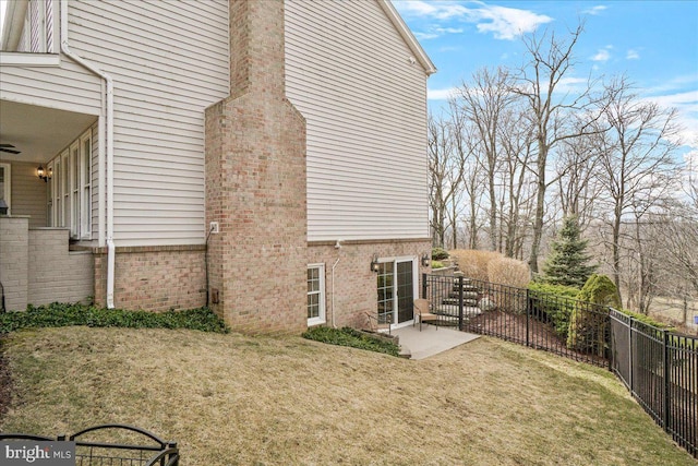 view of side of home featuring a patio area, a lawn, and fence