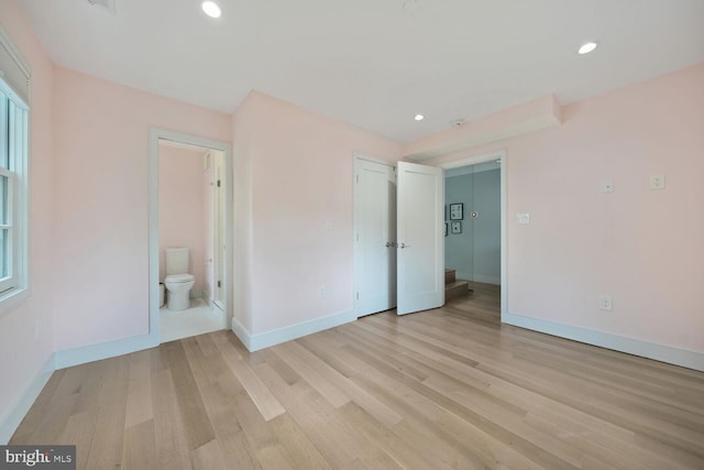 unfurnished bedroom with recessed lighting, connected bathroom, baseboards, and light wood finished floors