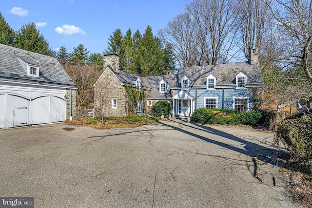 new england style home with a high end roof and a chimney