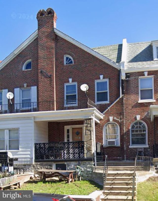 townhome / multi-family property featuring covered porch and brick siding