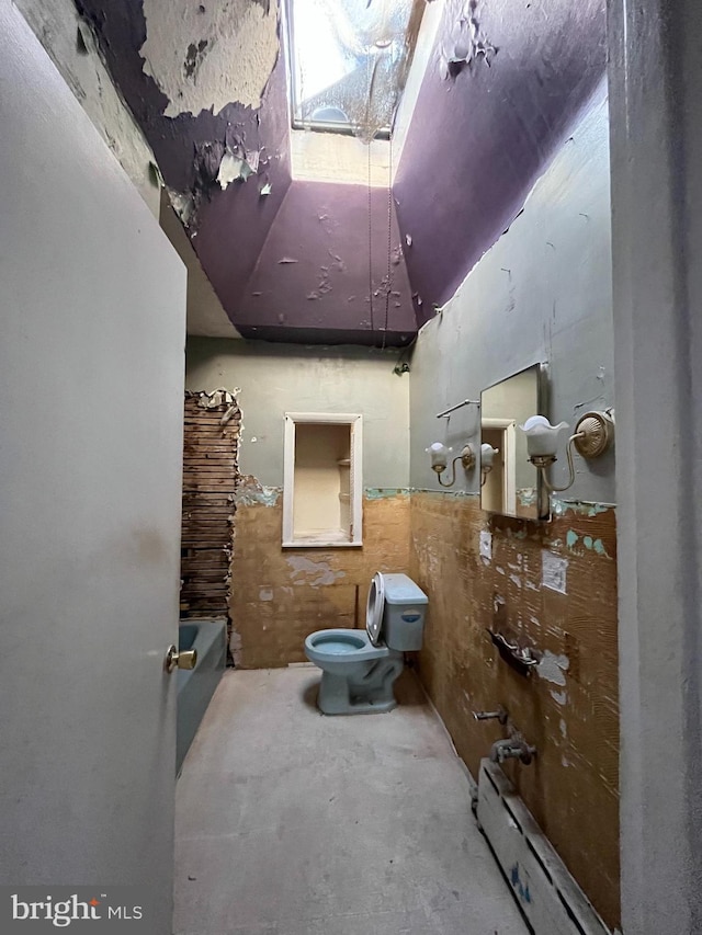 bathroom with toilet, concrete flooring, baseboard heating, and a washtub