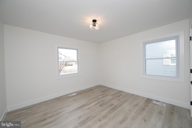unfurnished room featuring visible vents, baseboards, and light wood-style floors