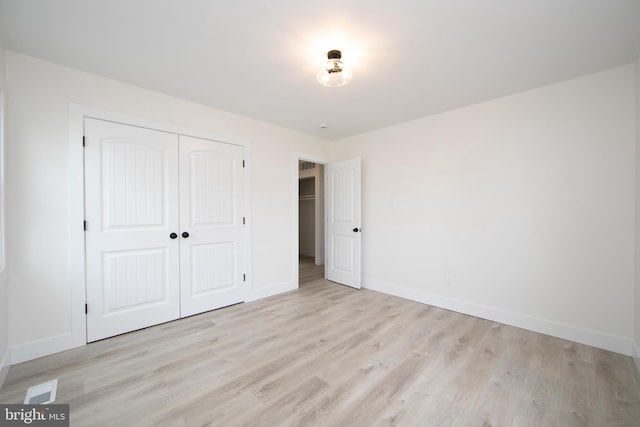 unfurnished bedroom featuring a closet, baseboards, and light wood finished floors