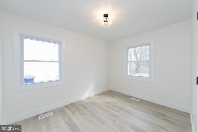 unfurnished room with visible vents, a healthy amount of sunlight, and baseboards