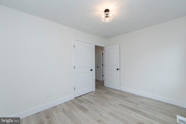 empty room featuring visible vents, light wood-style floors, and baseboards