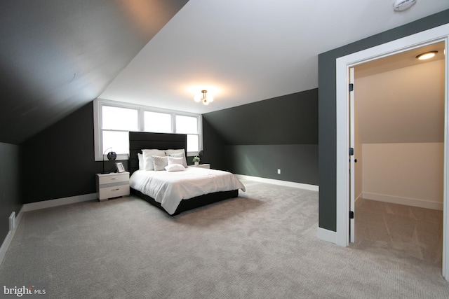 bedroom with lofted ceiling, baseboards, and light carpet