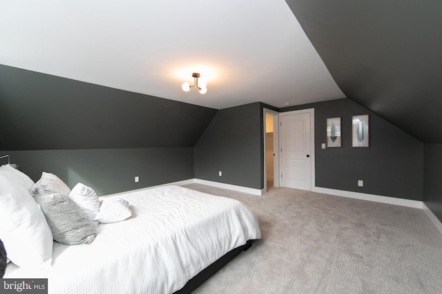 carpeted bedroom with lofted ceiling and baseboards