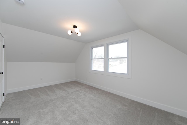 additional living space with lofted ceiling, light colored carpet, and baseboards